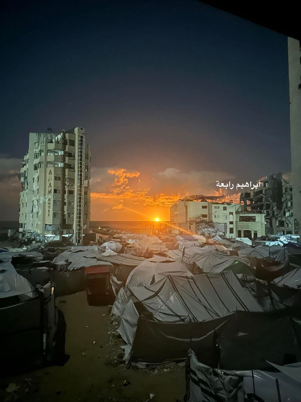 Палестинские беженцы ютящиеся в палатках в Секторе Газа наблюдают за горящий кораблем у побережья Газы